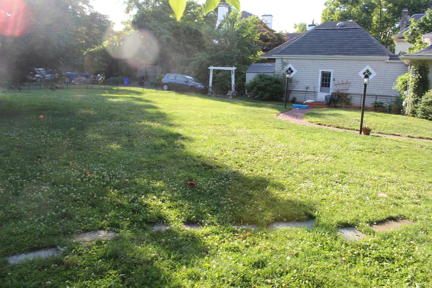 The open lawn of the play yard, fully fenced, with the house at the far end