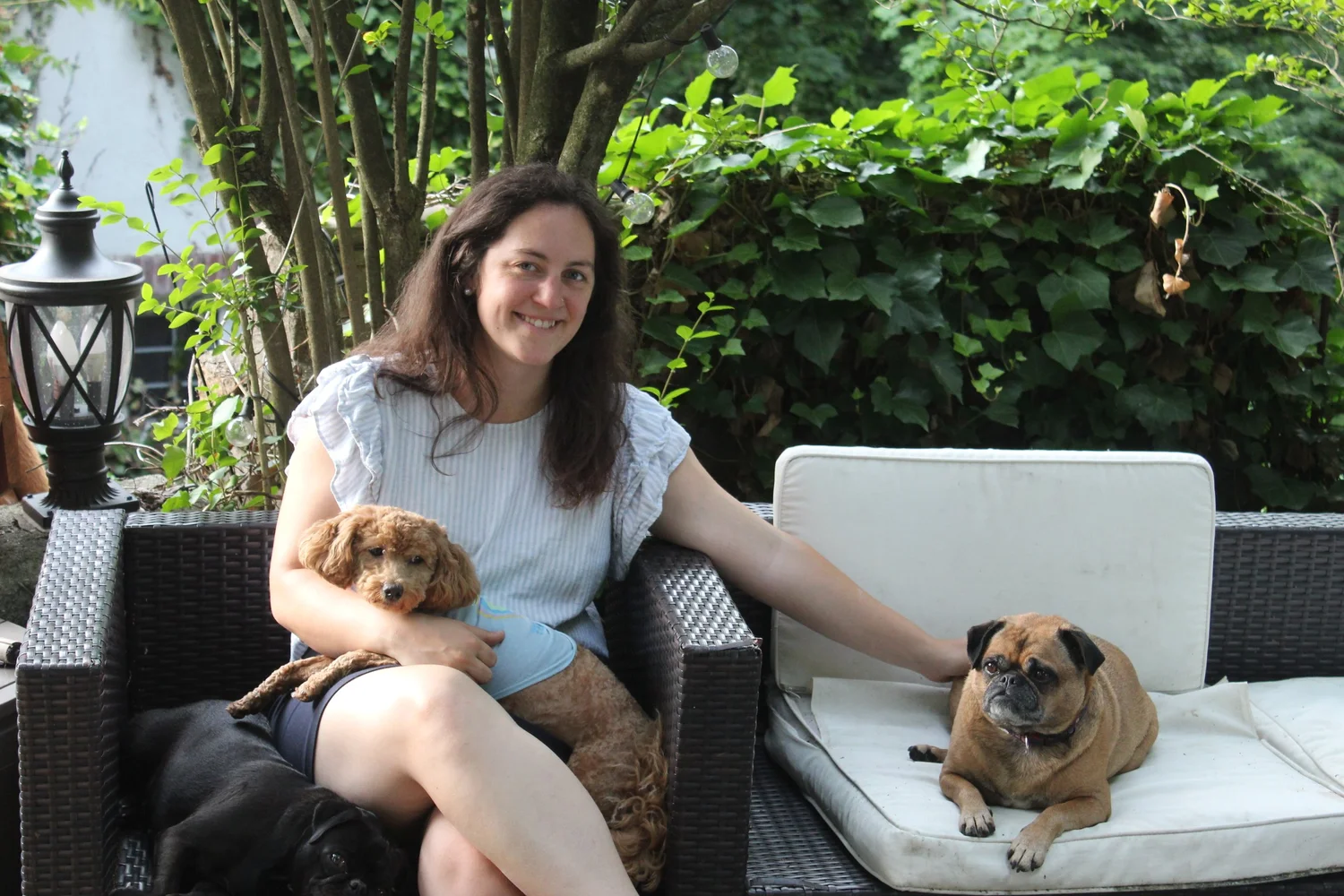 Amanda sitting on the patio sofa with three of the dogs resting beside her
